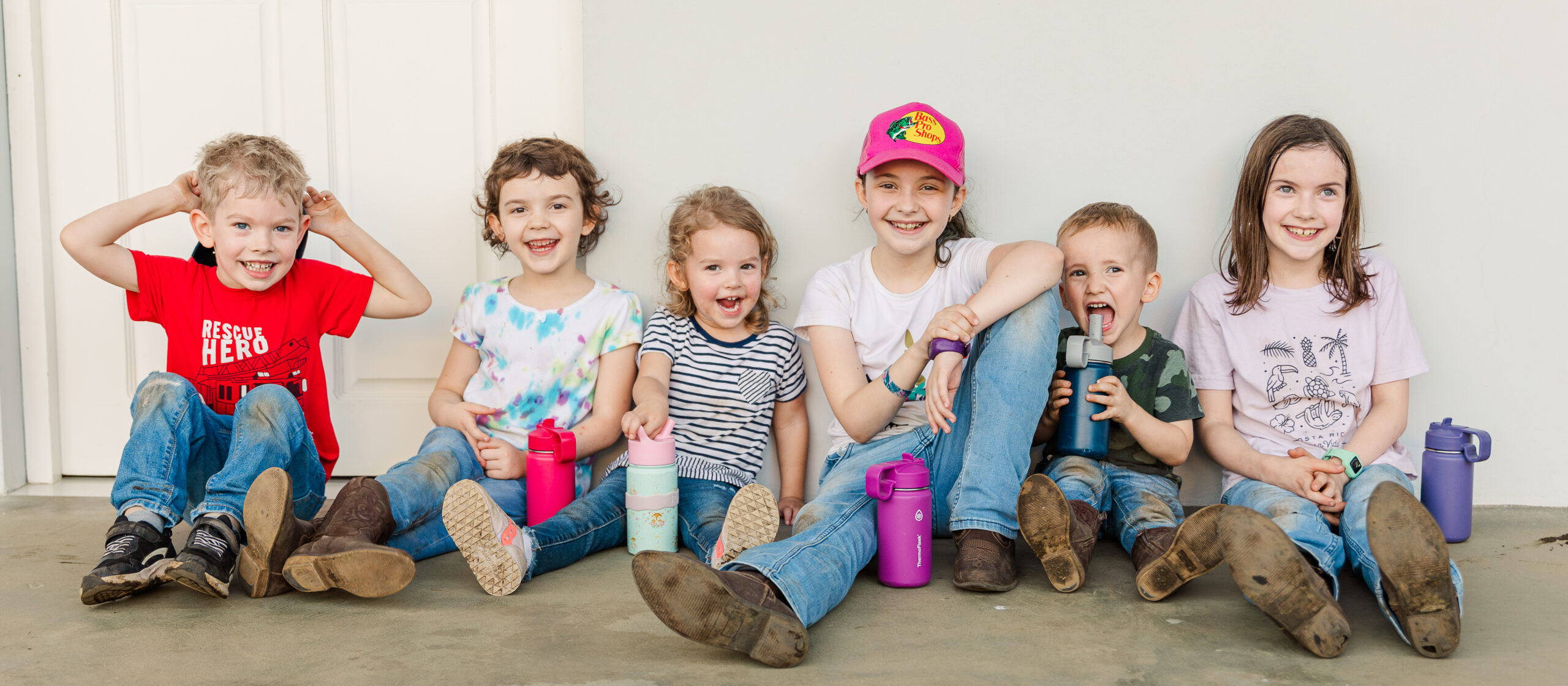 A group of young children sitting on a sidewalk and laughing