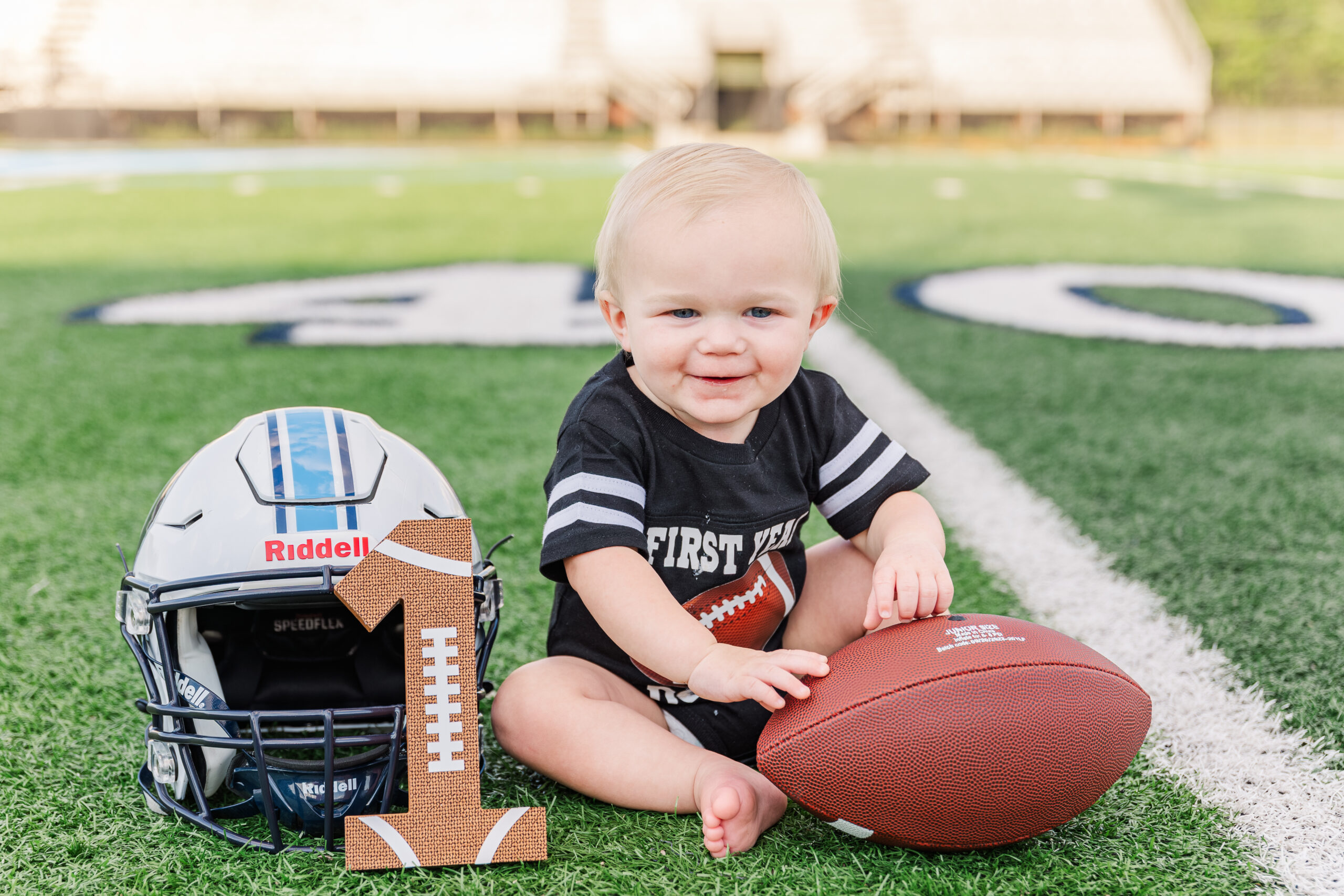 Football-themed birthday cake set on the Northside High School football field during Brantley's first birthday cake smash.