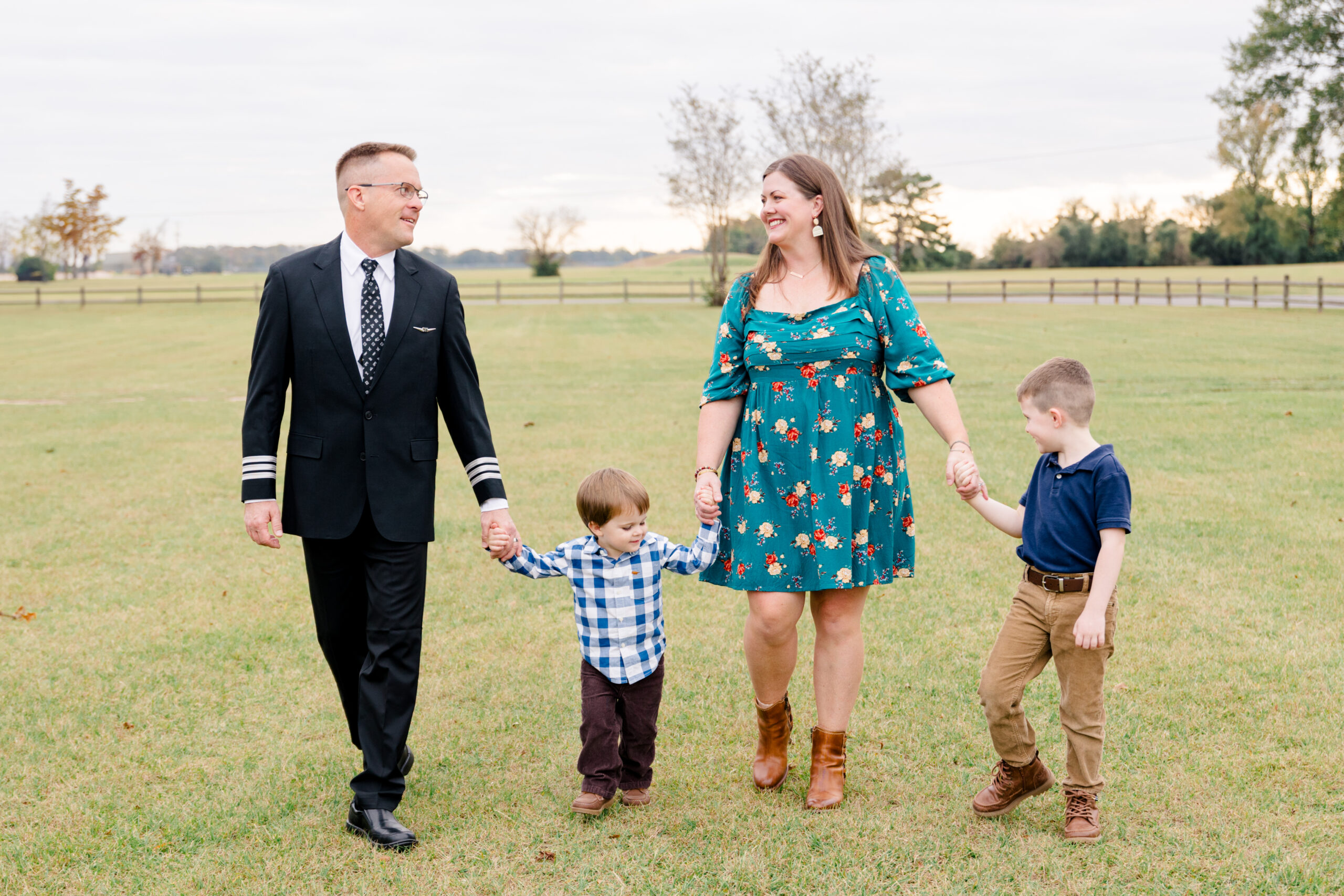 Family holding hands and walking towards the camera while looking at each other and smiling