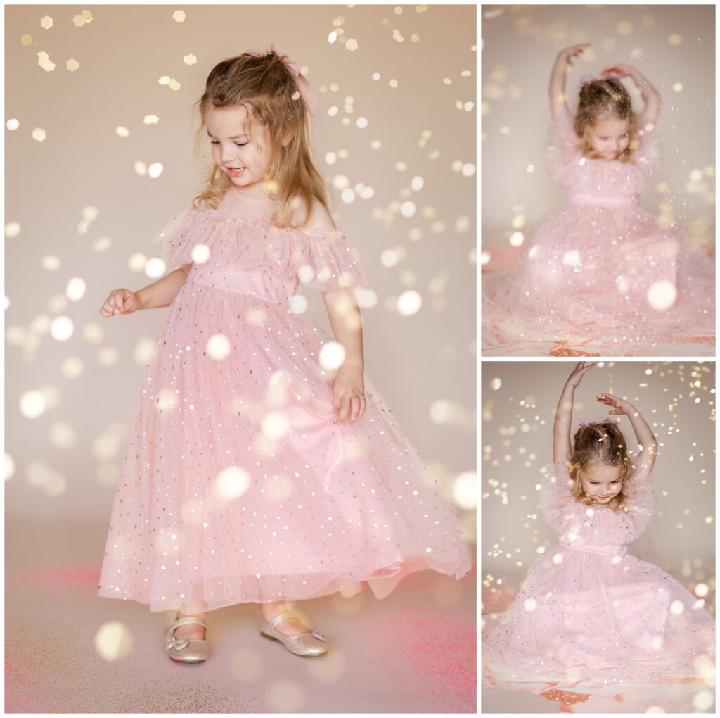 Little girl in a pink dress playing as glitter falls down in a glitter photoshoot