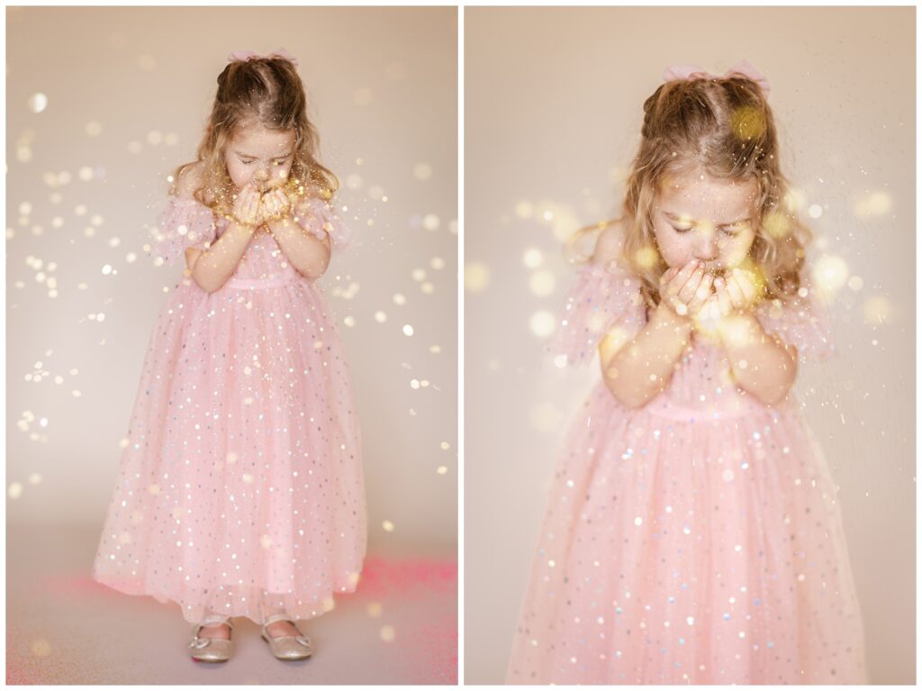 Little girl in a pink dress blowing glitter from her cupped hands towards the camera for a glitter photoshoot