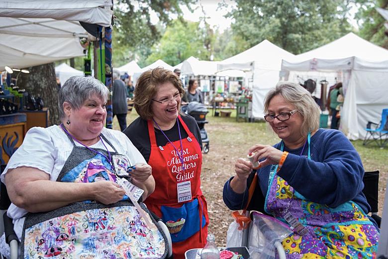 Three ladies sitting and laughing together at the Kentuck Festival.