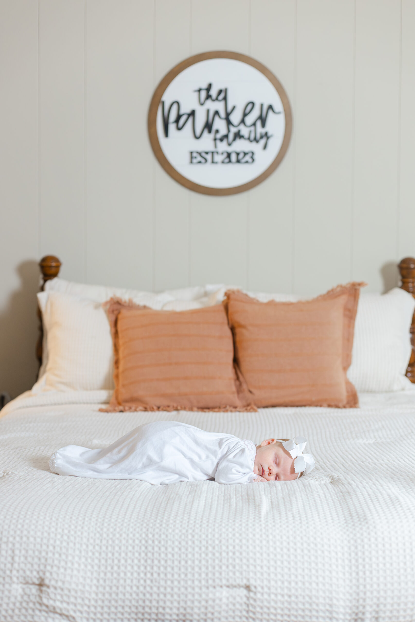 Newborn baby lying on a bed in a white gown and sleeping peacefully