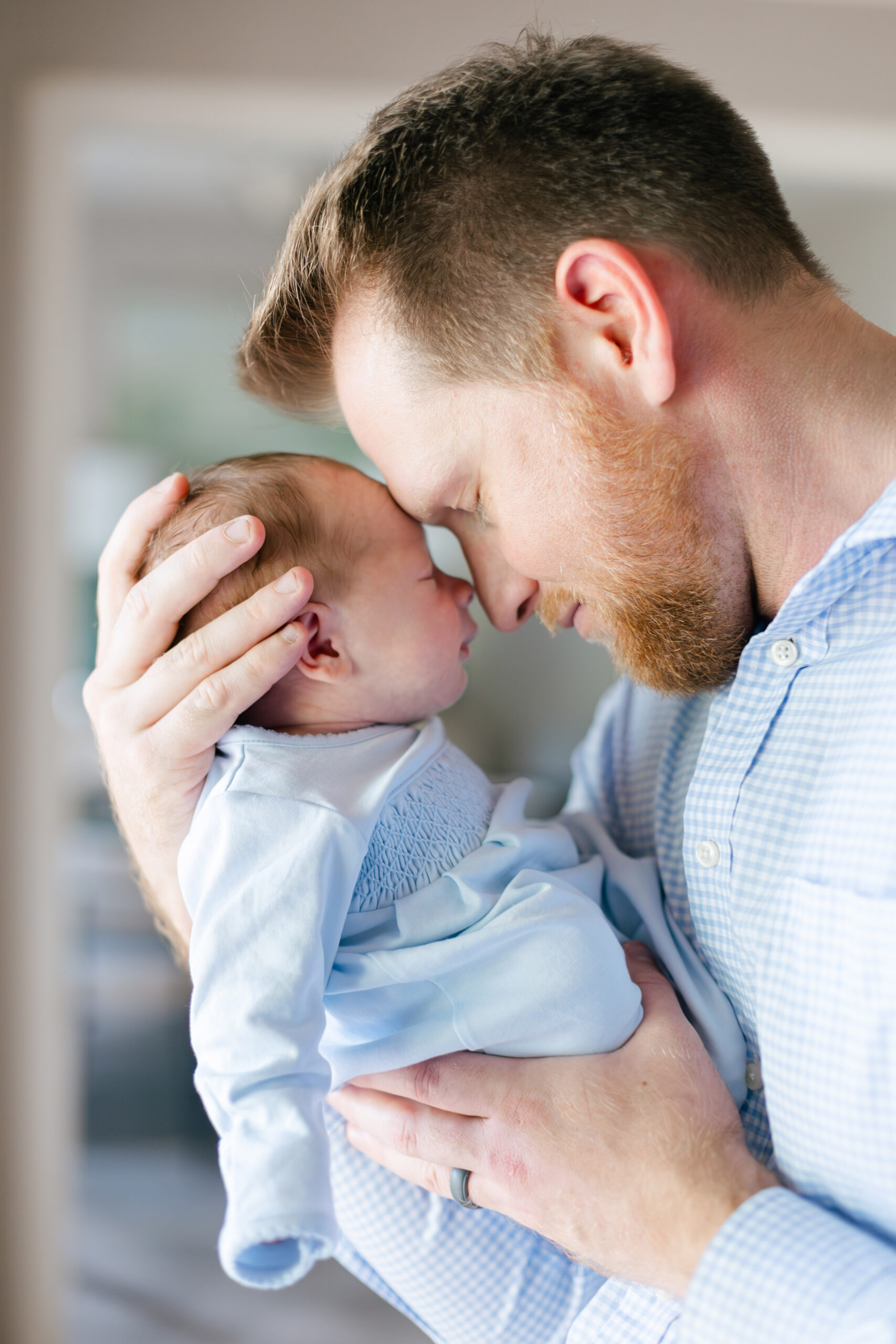 Tuscaloosa newborn photographer captures a father tenderly holding his newborn son forehead to forehead in soft natural light.