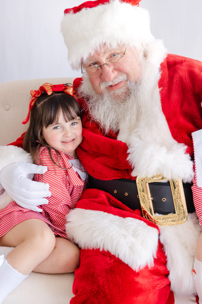 Toddler cuddled cheek to cheek with Santa in a genuine moment at a Tuscaloosa Santa mini session