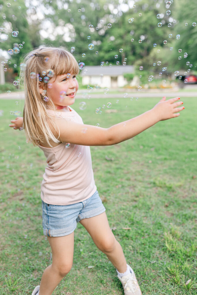 Little girl reaching for bubbles during a golden-hour summer session in West Alabama.