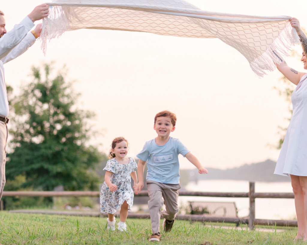 Two young siblings laughing together during an outdoor summer family session in West Alabama