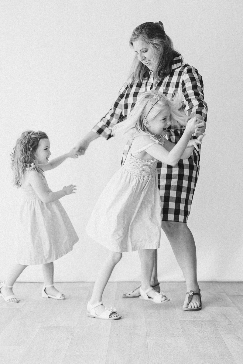 Mom laughing as she dances with her two daughters, captured by a motherhood photographer Tuscaloosa families trust